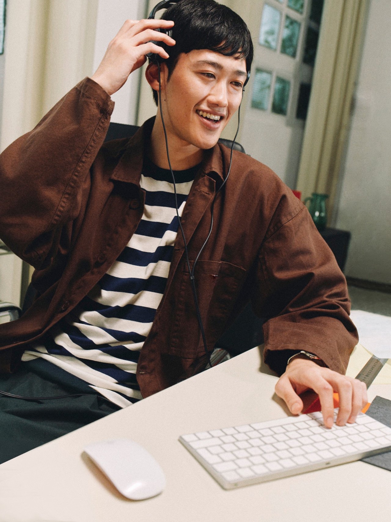 A person wearing headphones while working at a desktop computer.